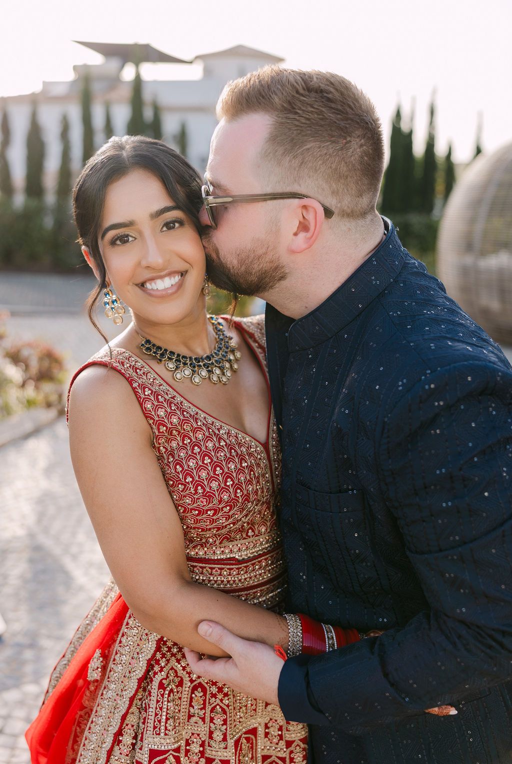 Romantic couple moment captured in formal attire against Mediterranean villa backdrop.