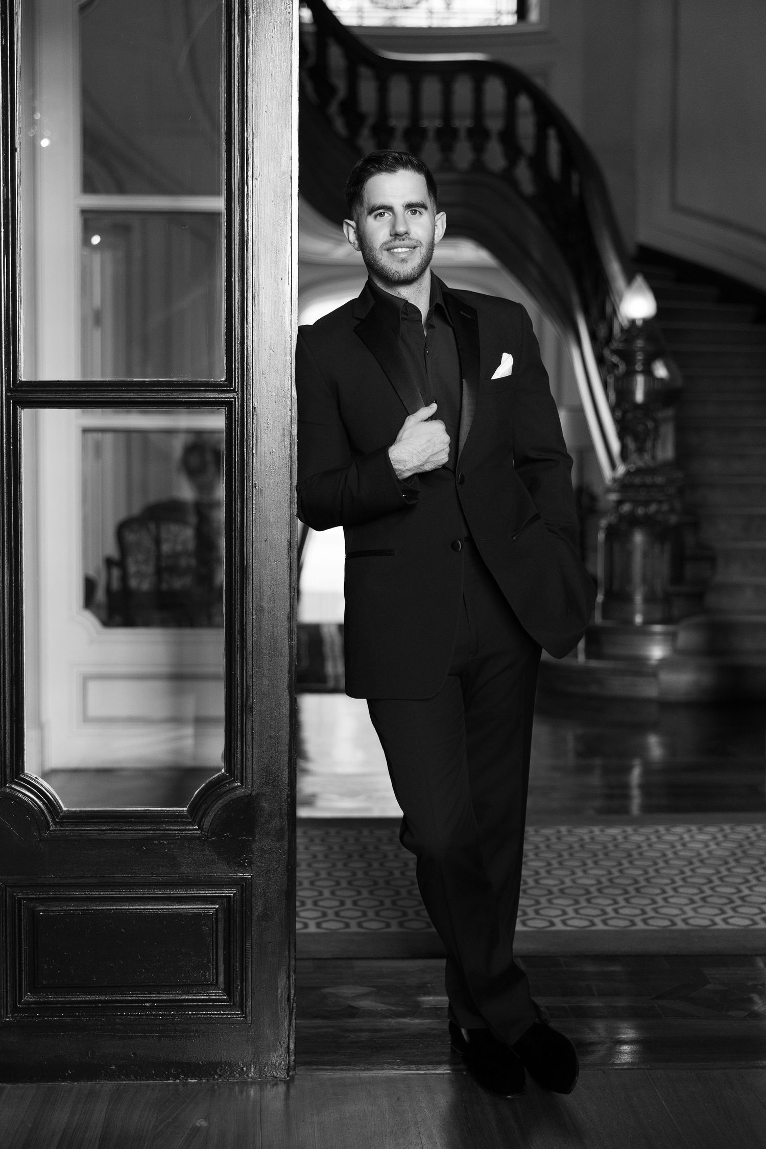 Black and white photos of a person in a suit walking through an elegant hallway.