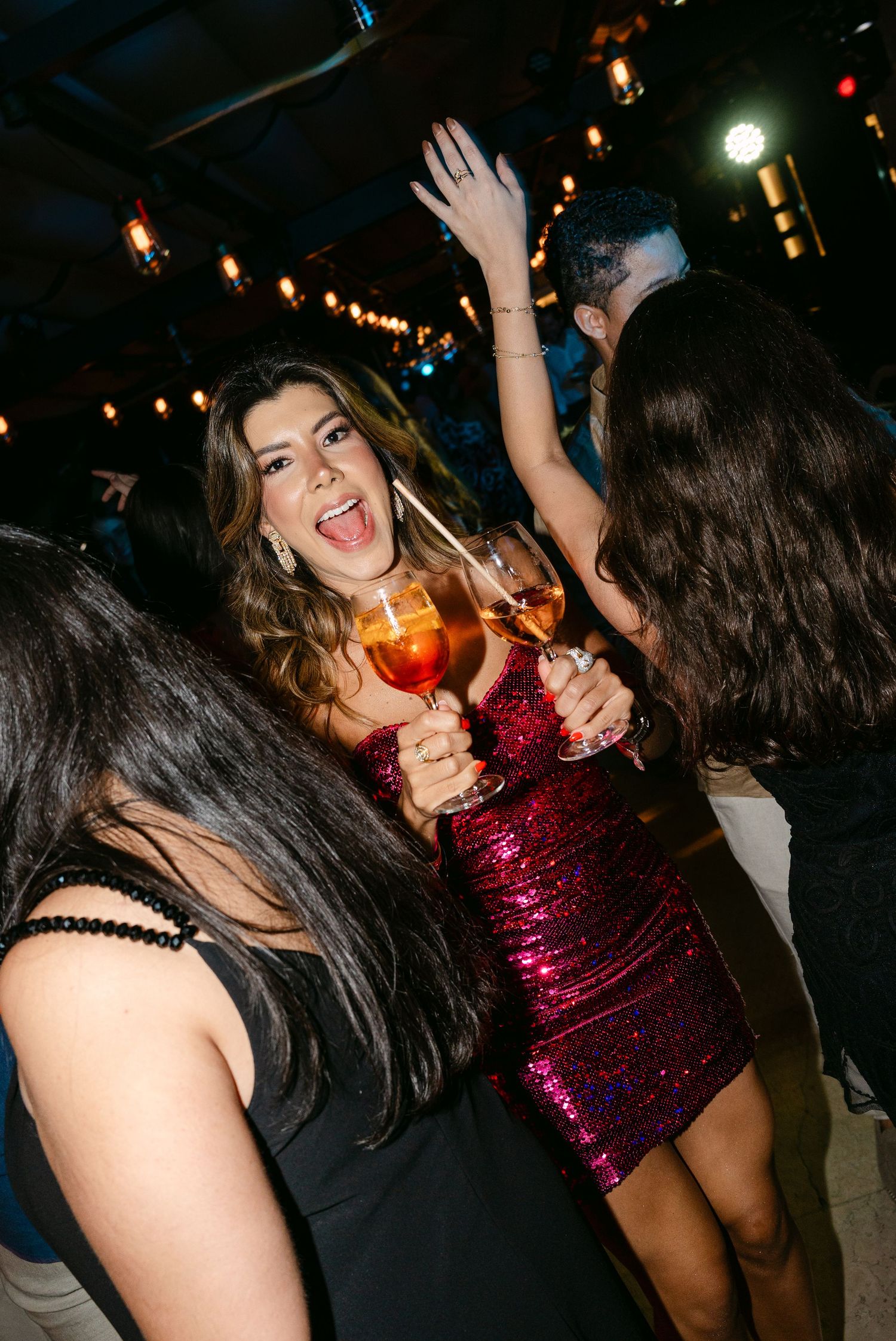 People dancing and celebrating at a lively nightclub party with colorful lights and festive atmosphere.
