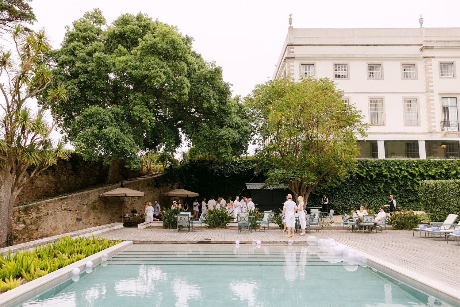 Elegant pool area with manicured gardens and classical architecture.