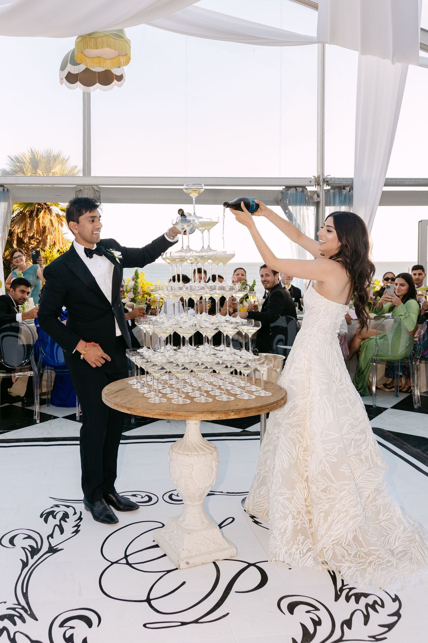 Celebratory champagne tower moment on a monogrammed dance floor at an elegant reception.