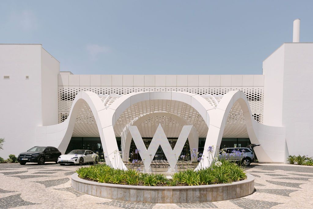 Modern white architectural structures with geometric shapes and curved walls against a bright blue sky.