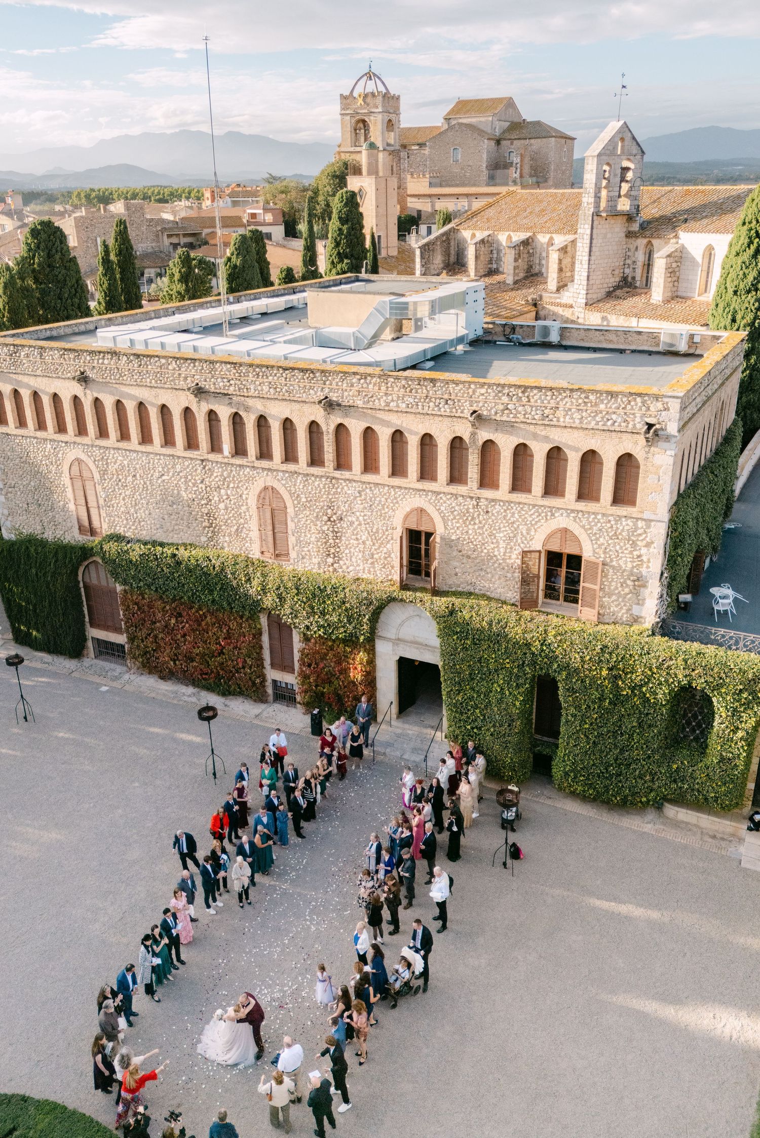 Aerial view of wedding guests forming lines in a historic monastery courtyard.