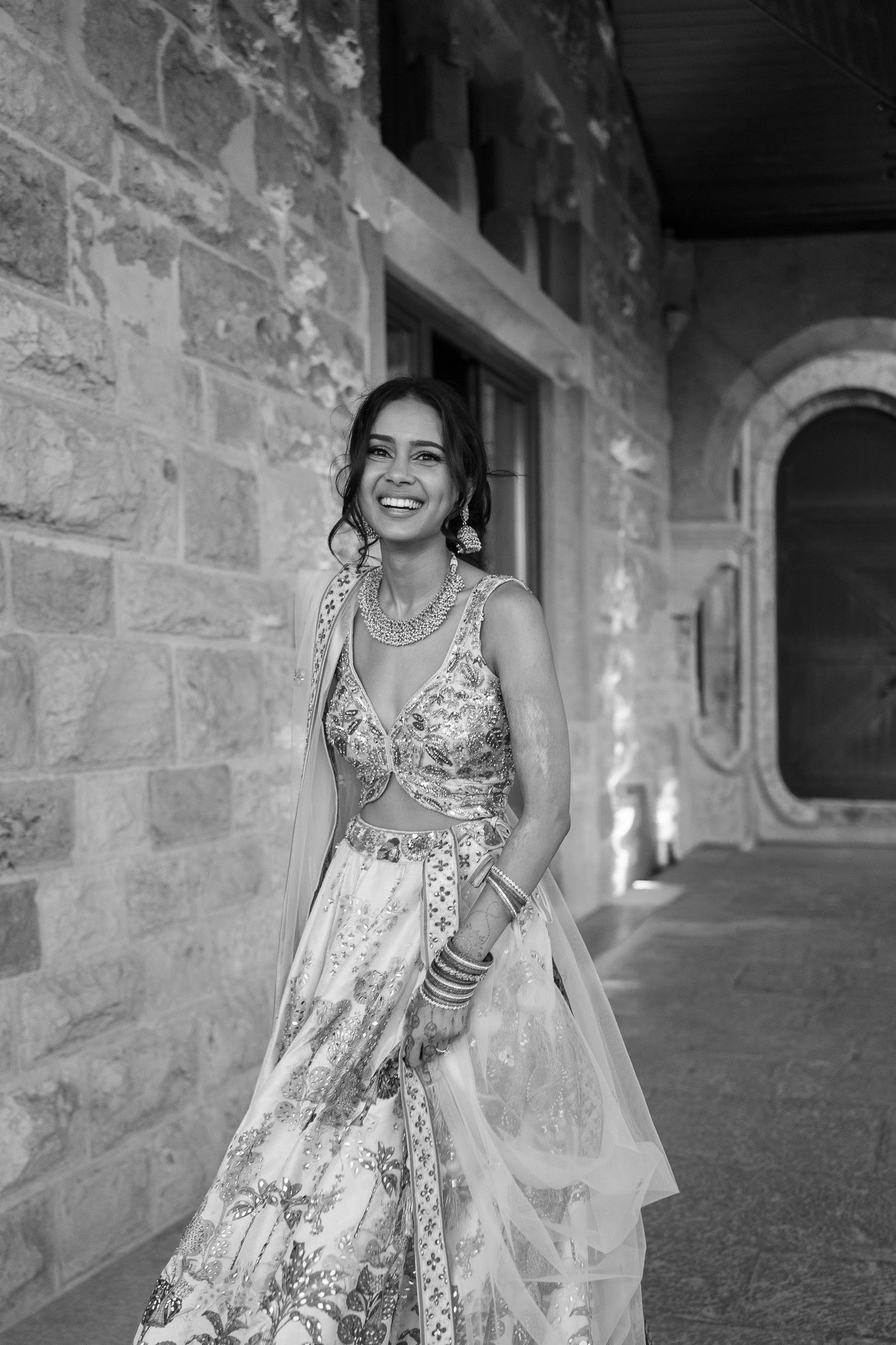 Black and white portrait in a stone archway corridor with elegant architectural details.