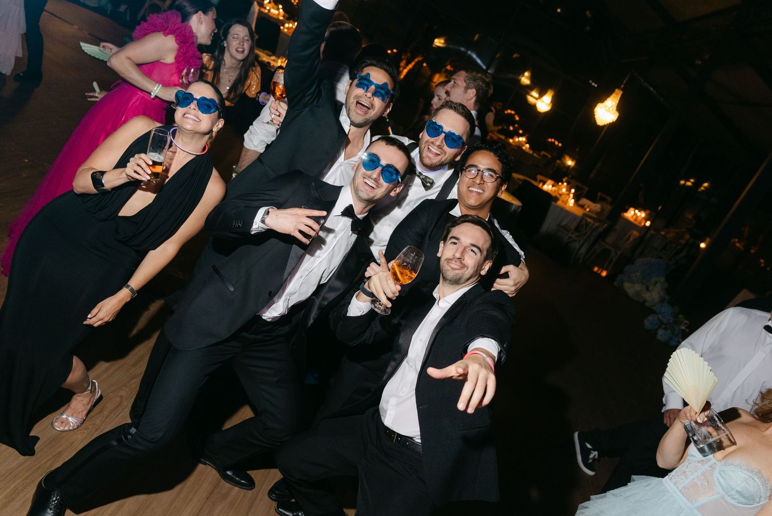 Wedding reception dance party with guests enjoying festivities under colorful lights.