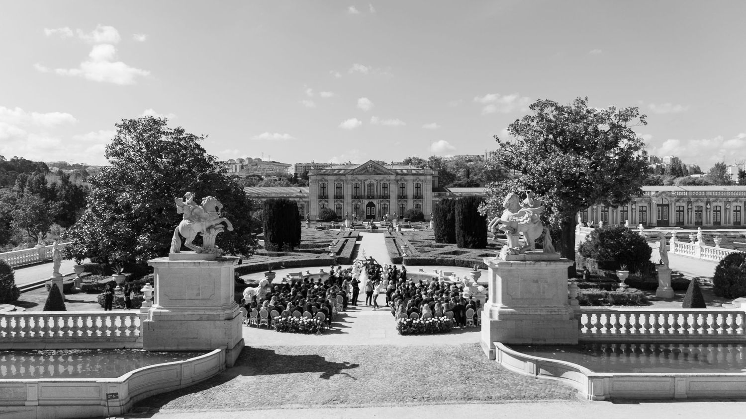 Panoramic view of a formal garden wedding venue with stone balustrades and symmetrical landscaping.