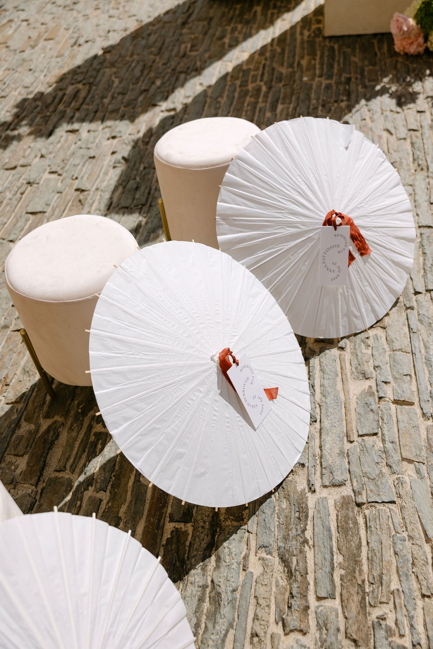 White paper parasols arranged on a cobblestone pathway with delicate red accents.