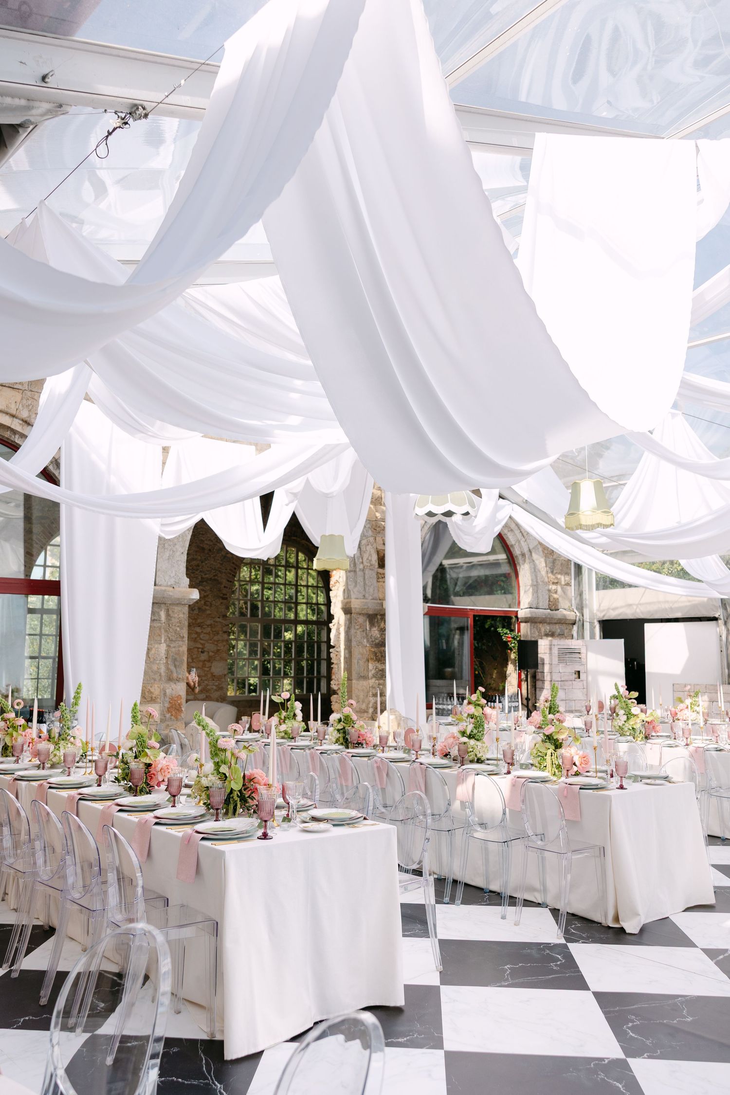 Luxurious wedding reception venue with white drapes and checkered floor pattern.