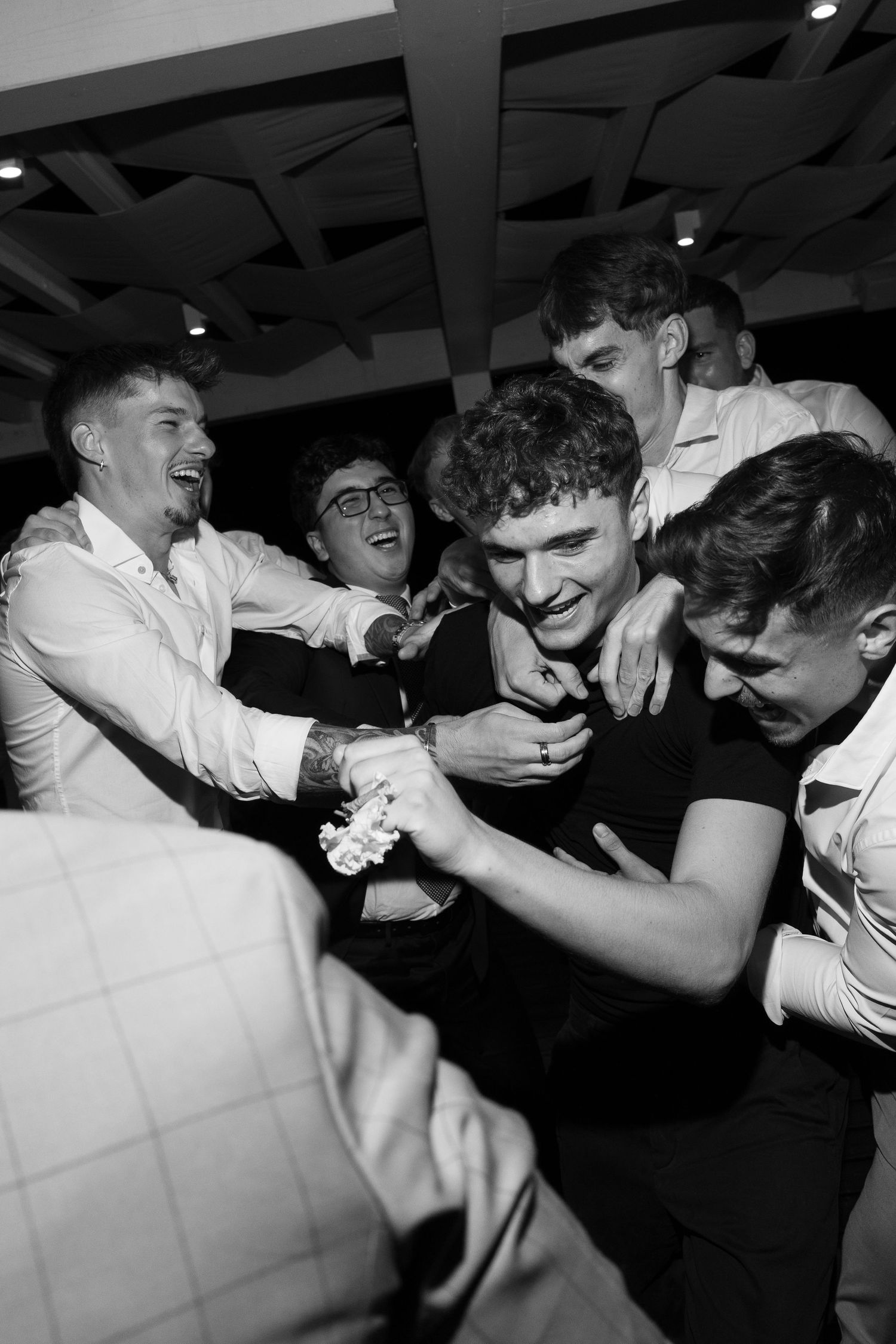 Energetic black and white photo of wedding guests dancing and celebrating at reception.