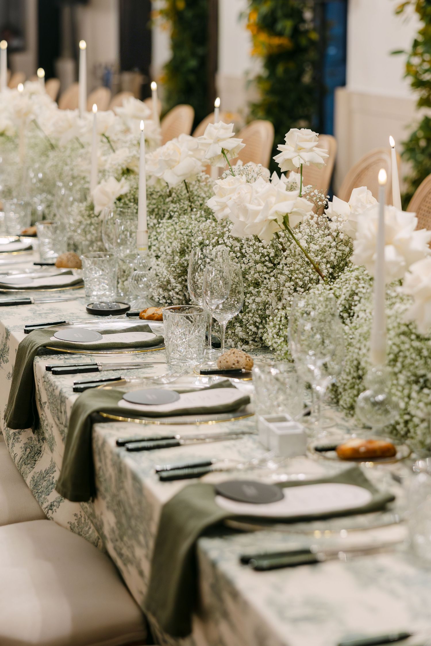 Elegant wedding table setting with white flowers and baby's breath centerpieces along a lace tablecloth.
