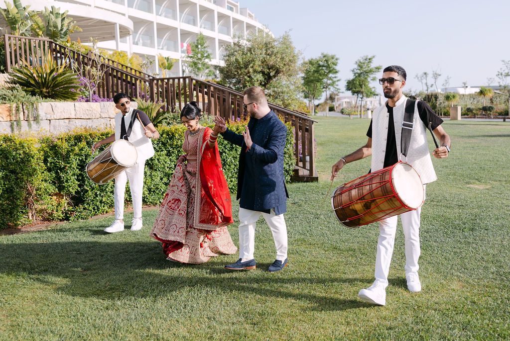 People walking through a garden path in formal attire during a sunny outdoor event.