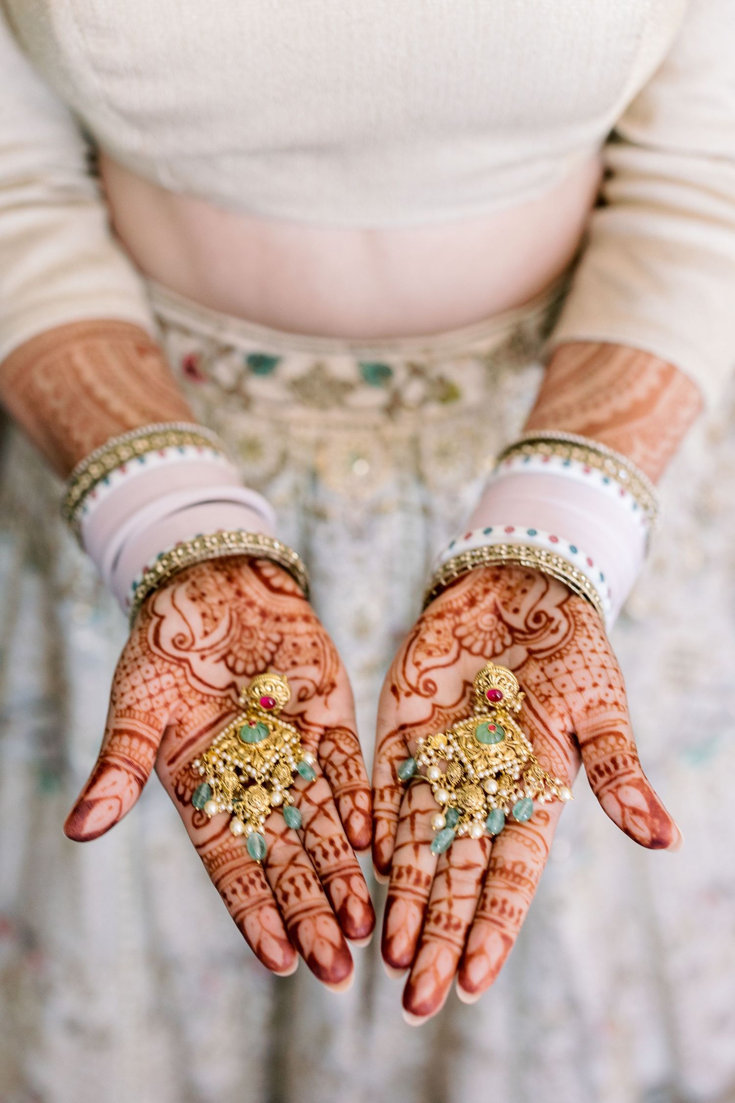 Detailed view of henna-adorned hands displaying traditional wedding jewelry.