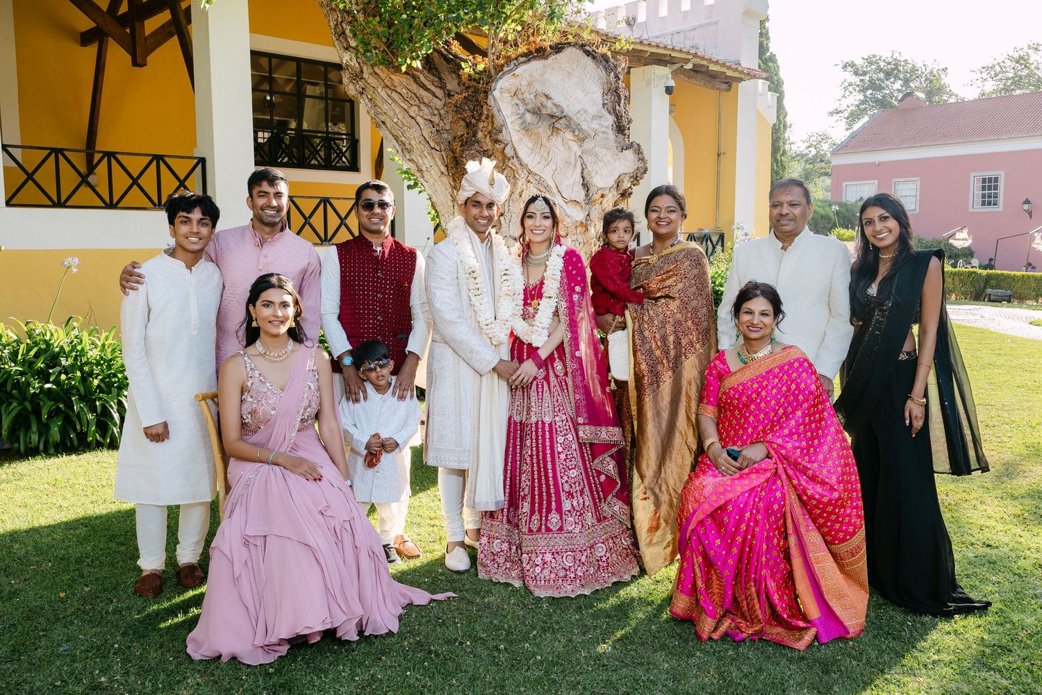 Wedding party members gather for a group photo in traditional Indian and western fusion attire.