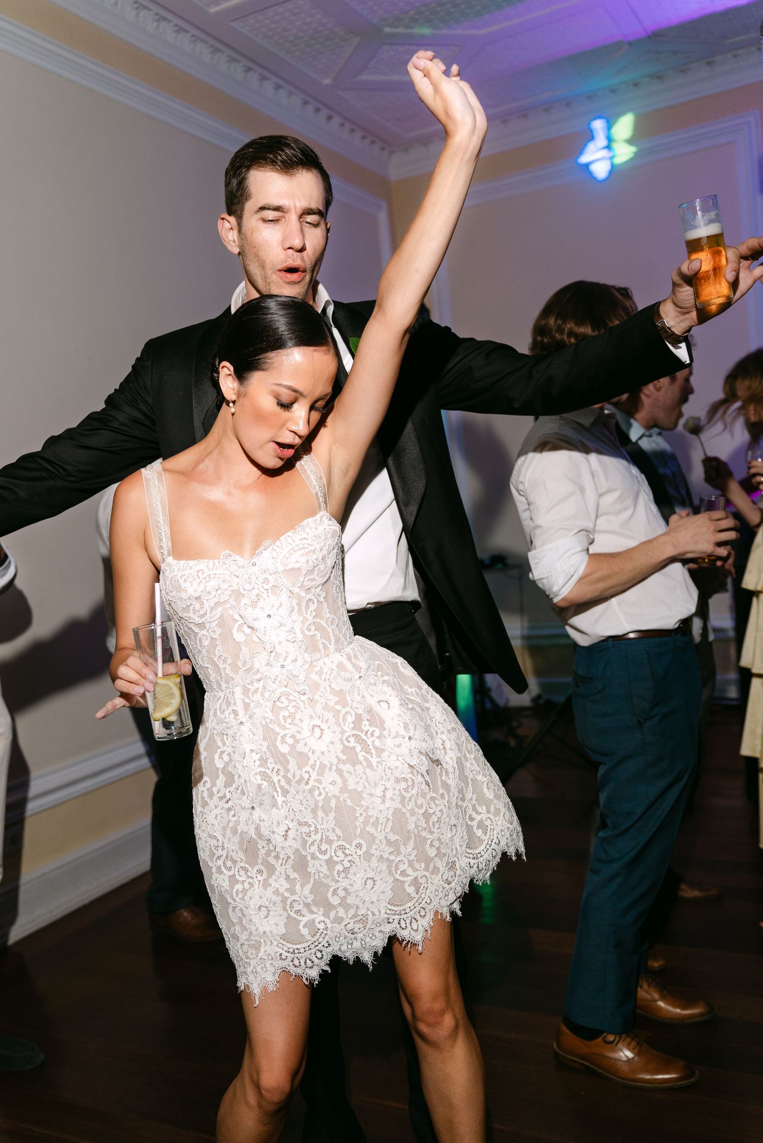 Wedding reception dance floor filled with joyful celebration and dancing in white lace dress.