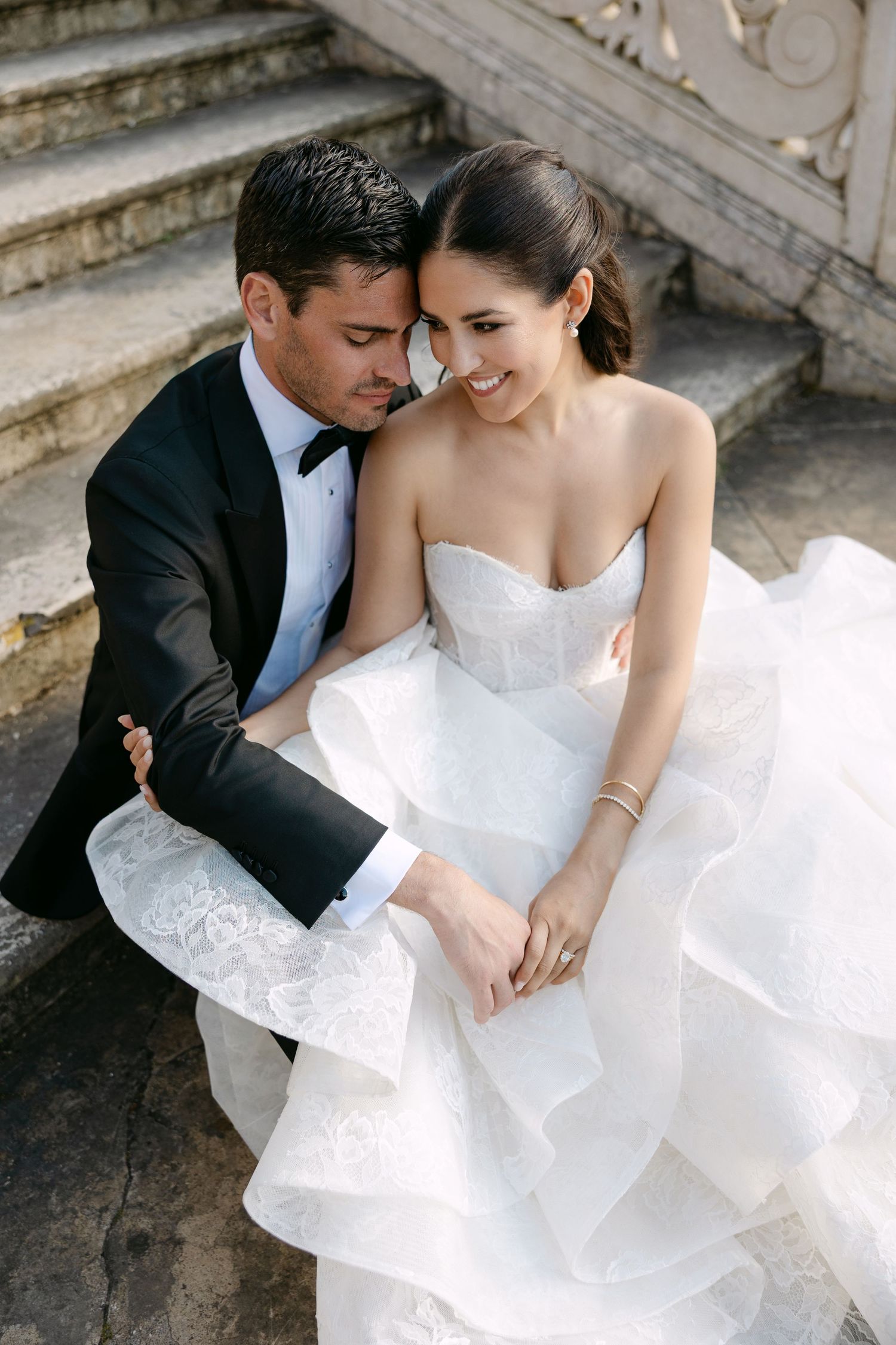 Intimate wedding portrait showing tender moment between couple on ornate stone steps.