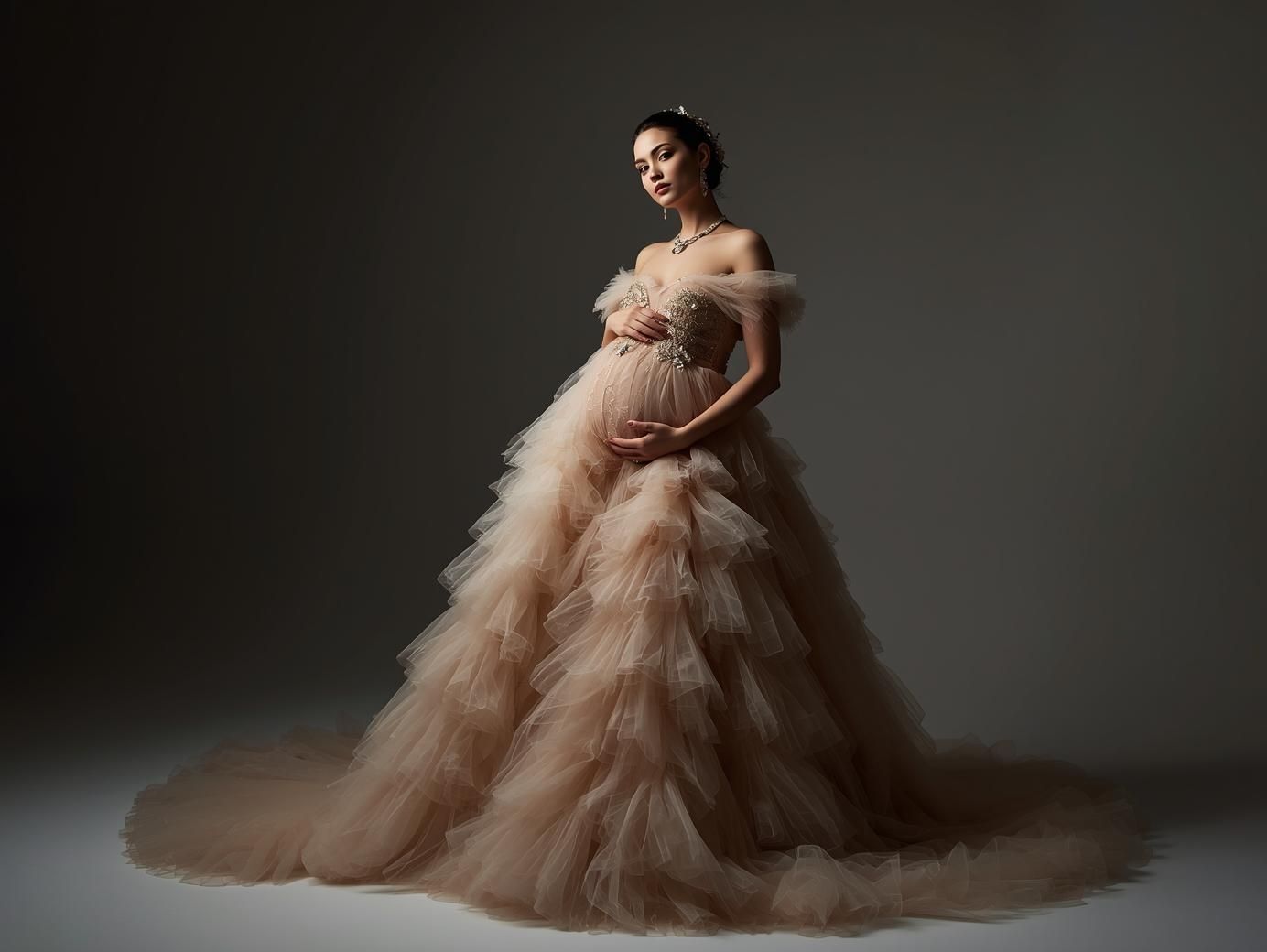 A model in a flowing blush pink tulle gown poses gracefully against a dark studio backdrop.