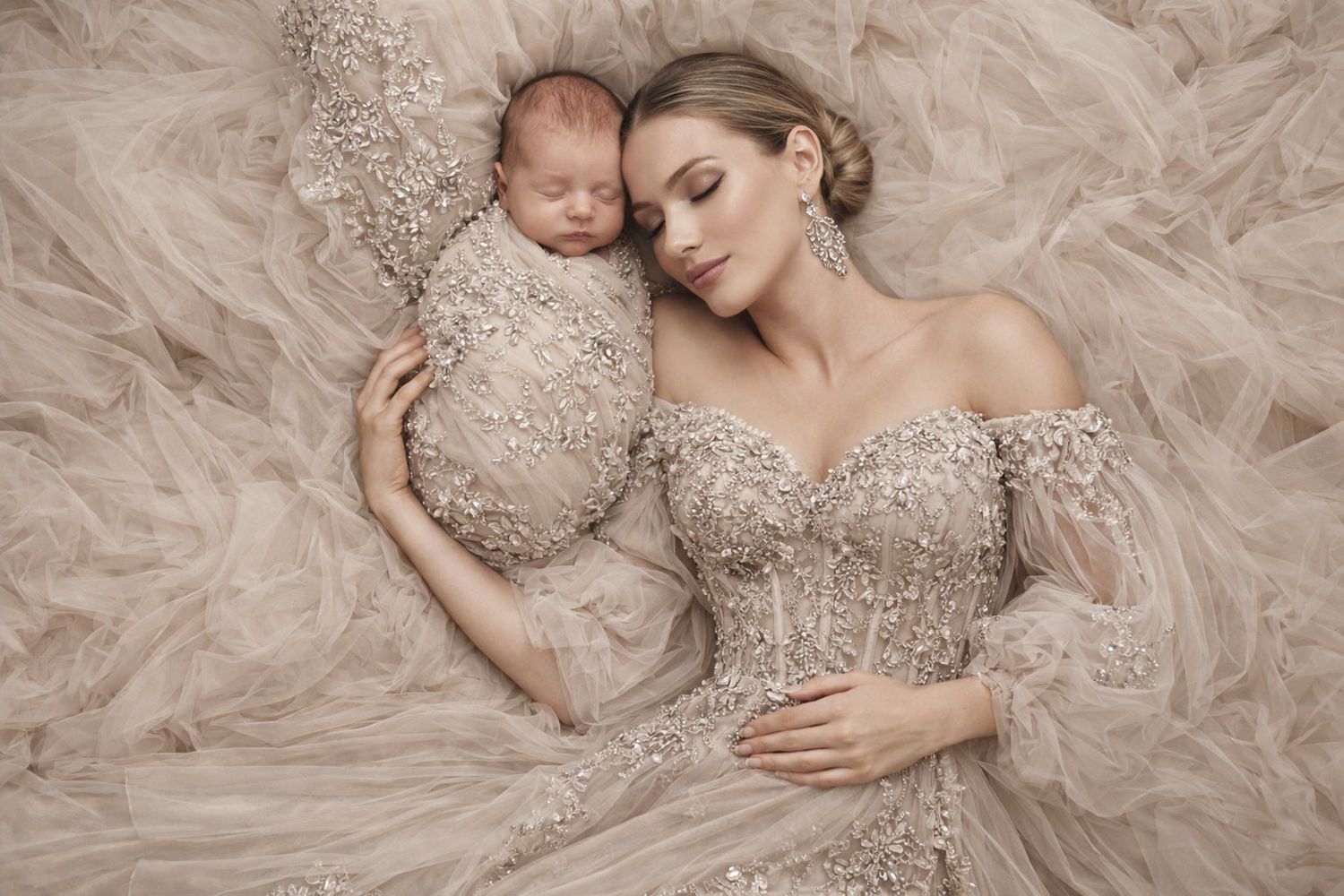 A bride in a champagne-colored beaded gown poses elegantly on soft tulle fabric in a romantic bridal portrait series.