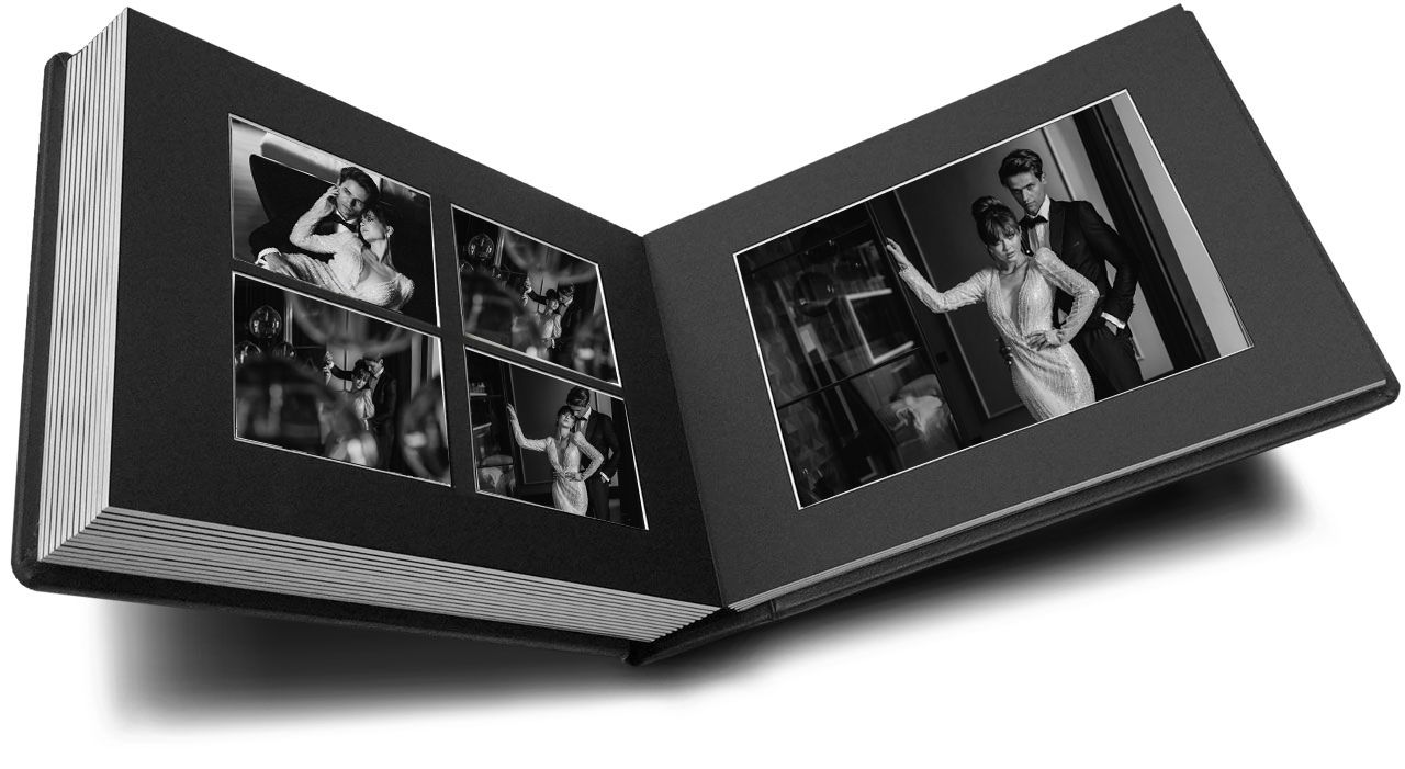 Black and white photo album open displaying elegant portrait photographs mounted on dark pages.