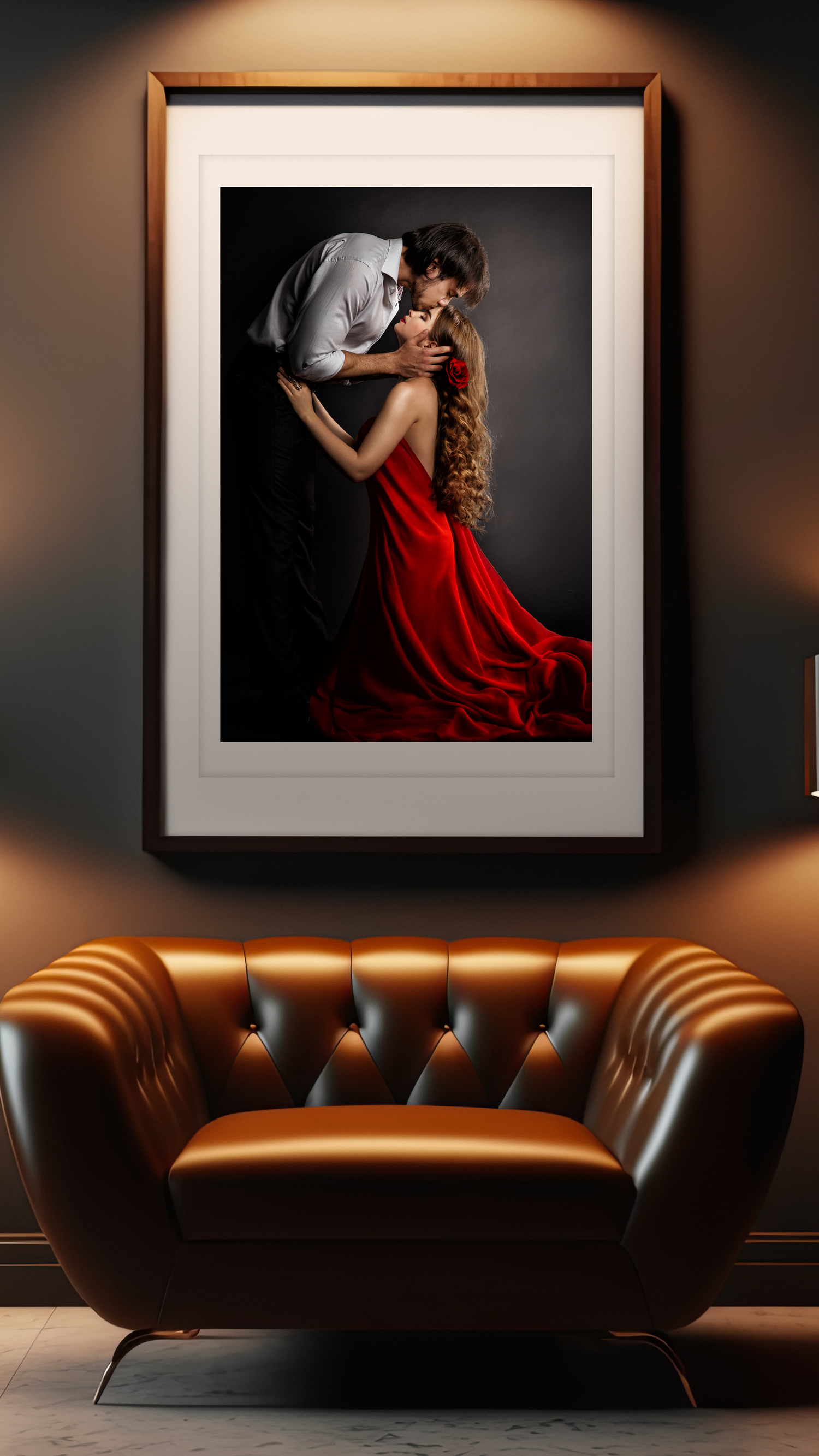 A couple embraces passionately, woman in flowing red gown, framed art print above a luxurious brown leather tufted armchair.