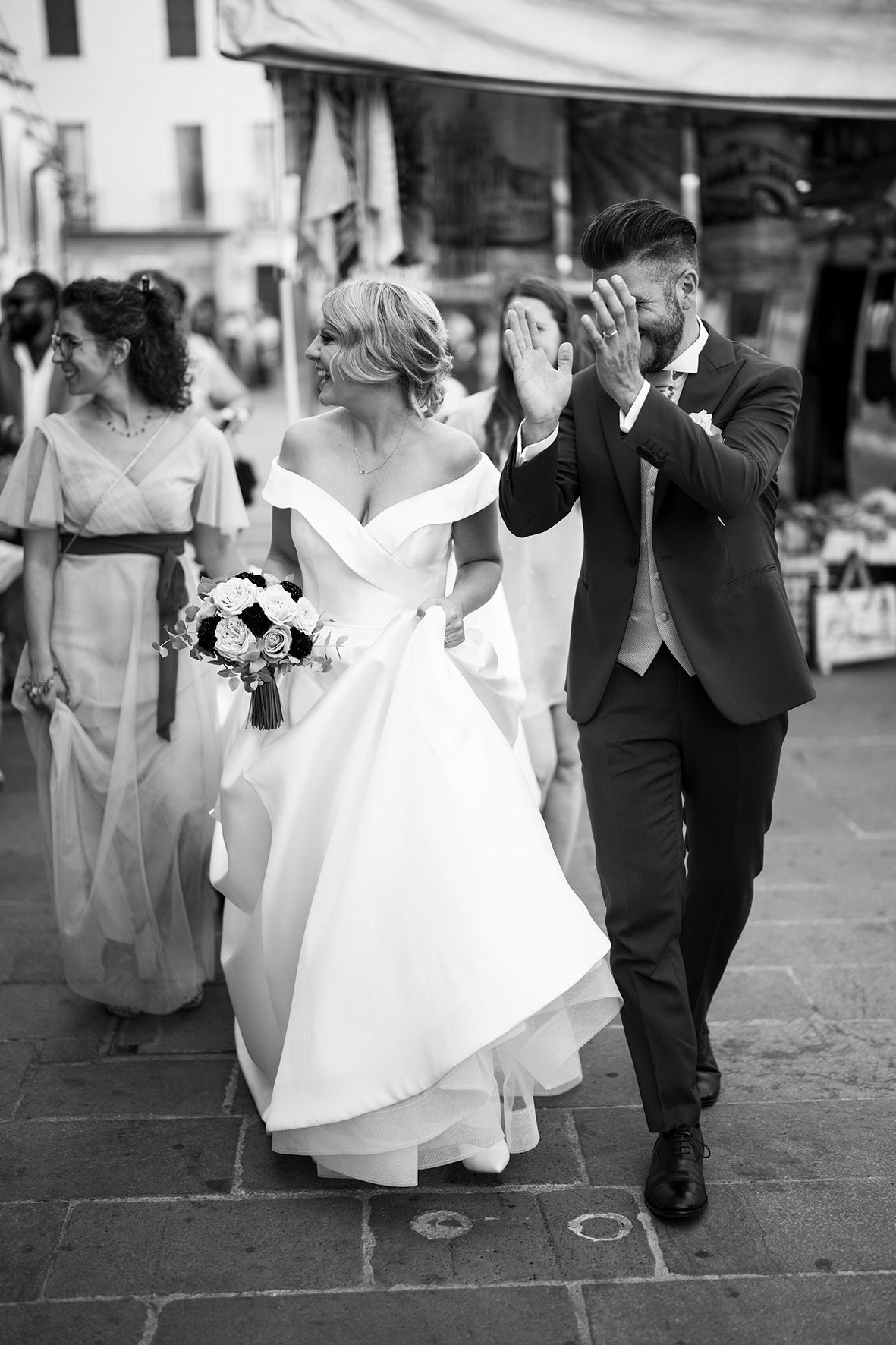 Black and white wedding photos showing couple walking together on stone pavement.