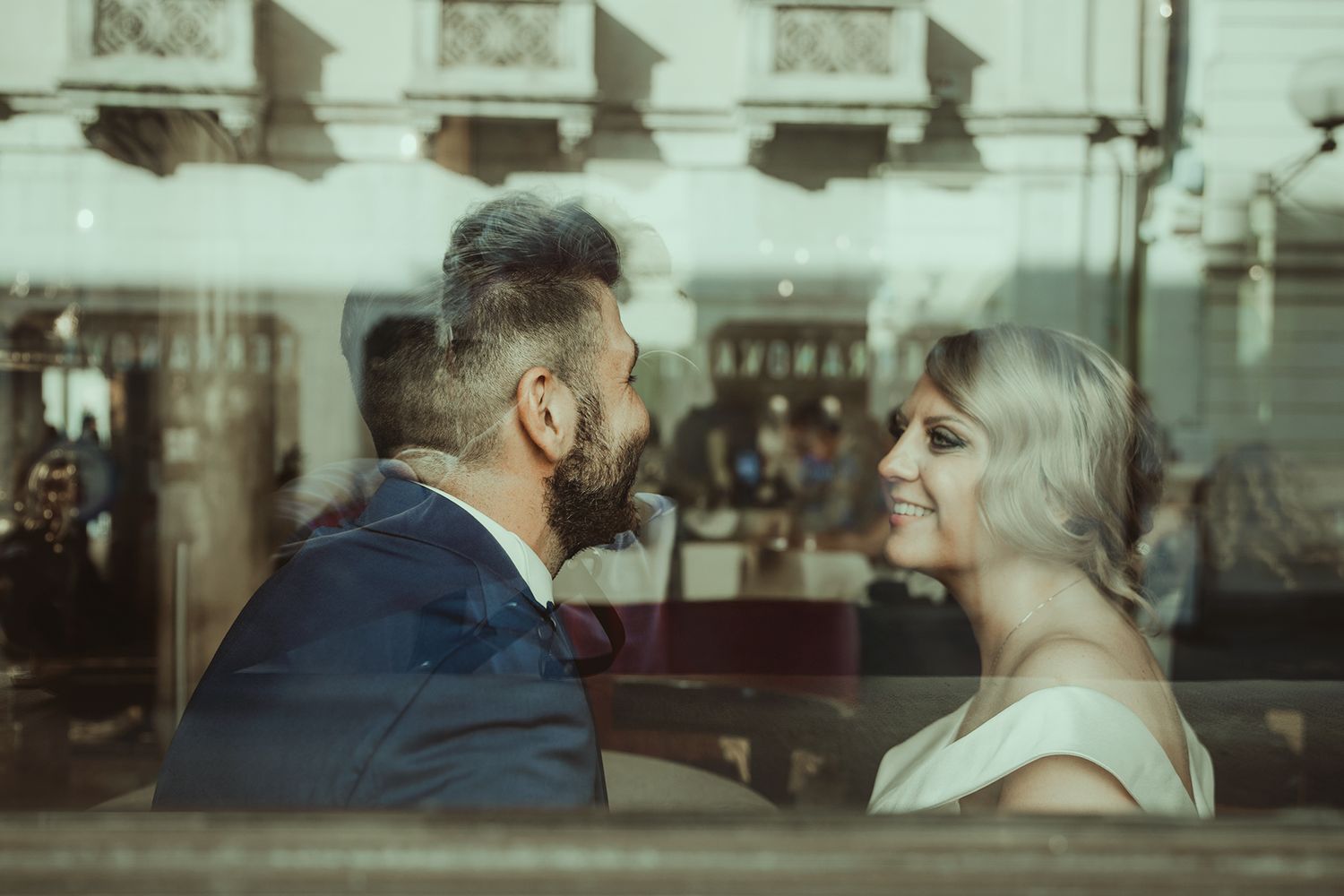 Artistic wedding photography through reflective glass showing soft, muted tones.
