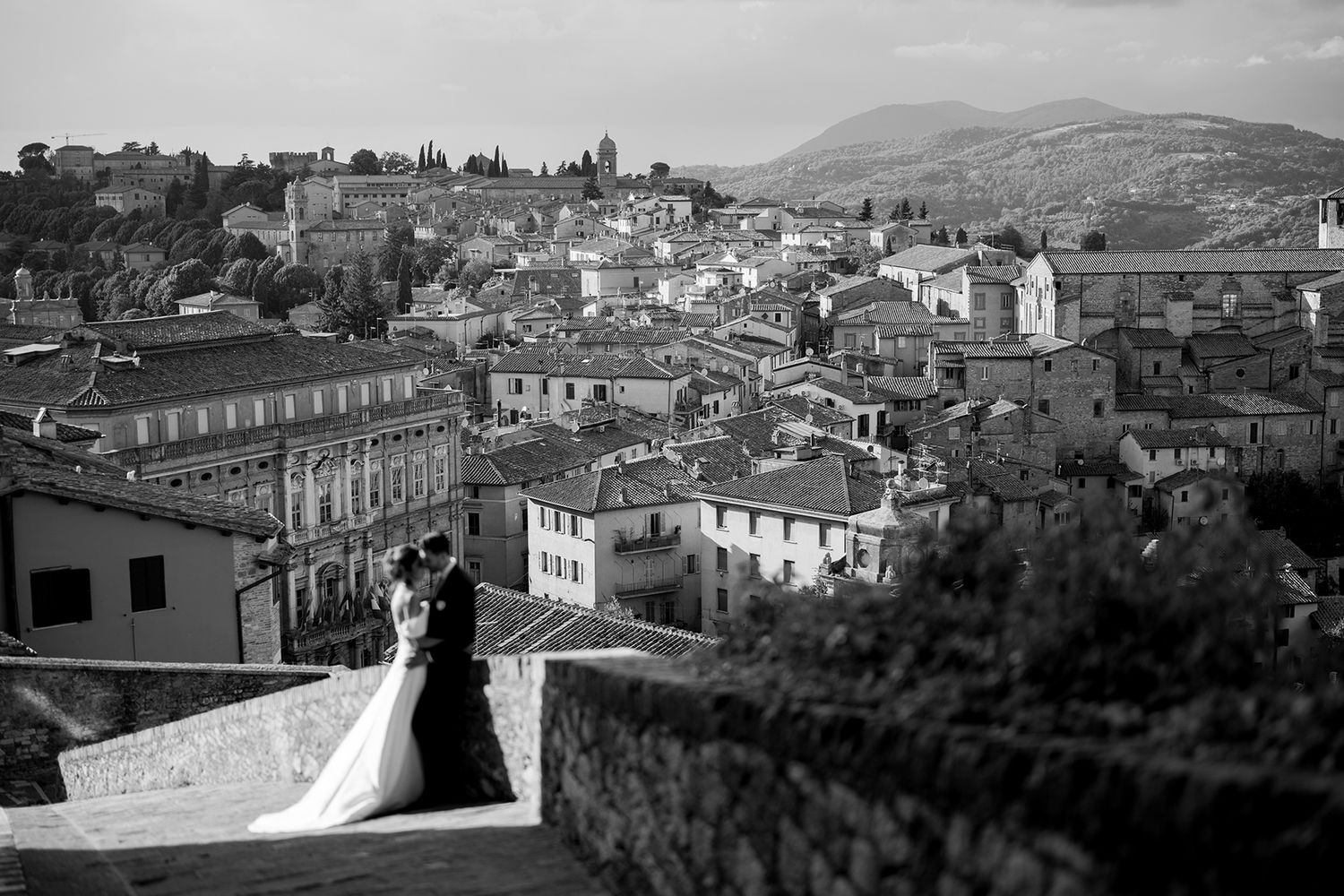 Panoramic view of an Italian village nestled in rolling hills with traditional architecture.