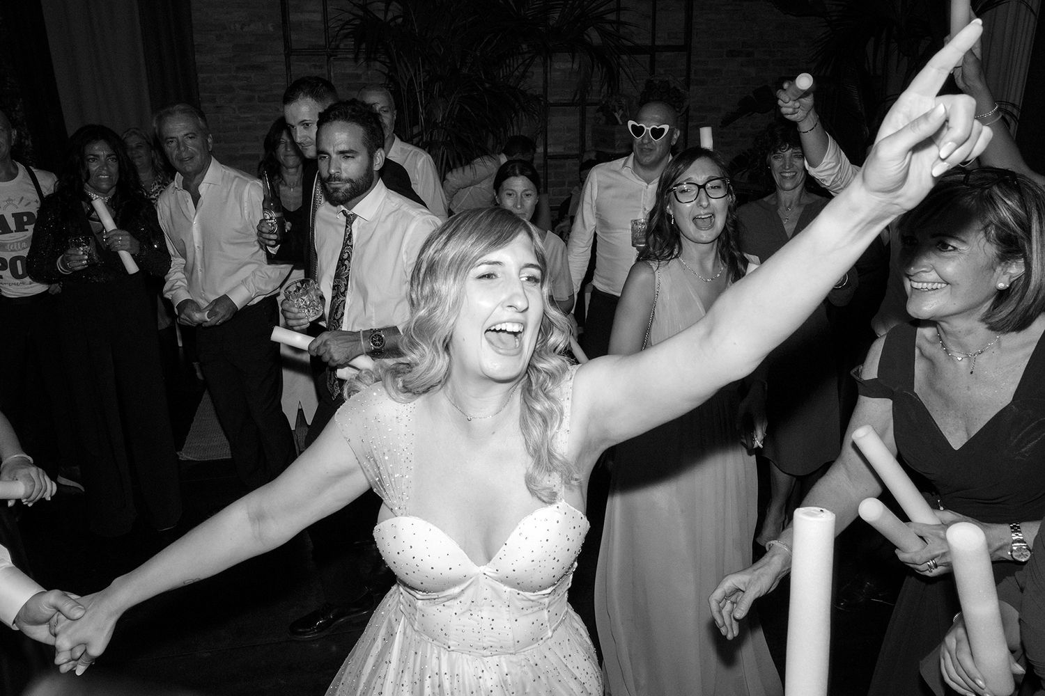 Joyful dancing and celebration on a dimly lit wedding reception dance floor.
