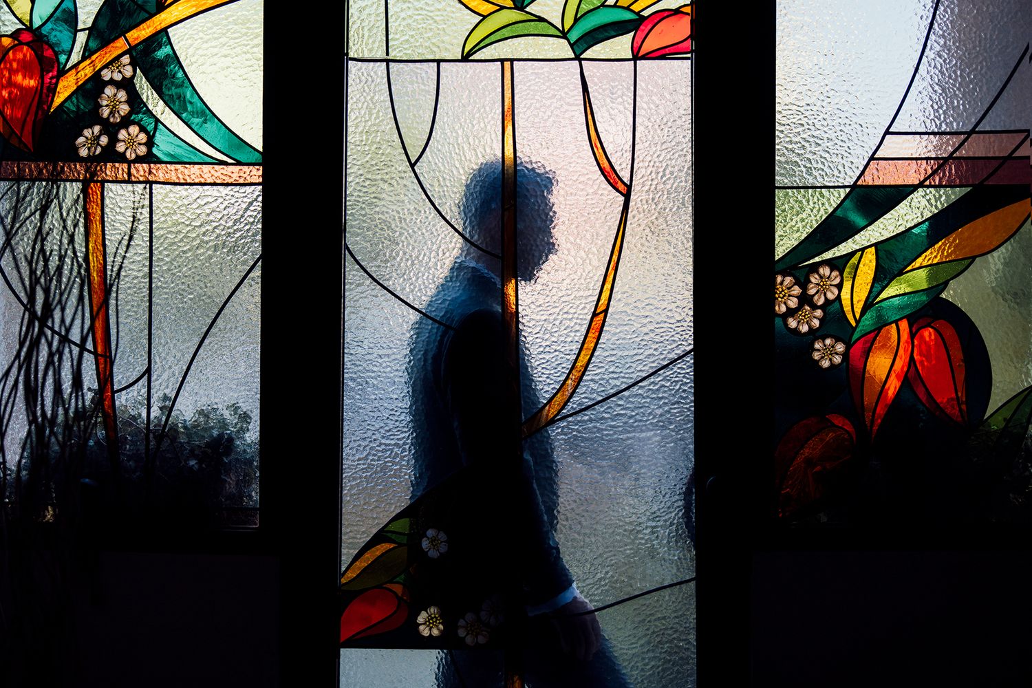 Artistic silhouettes against colorful stained glass windows creating abstract patterns.