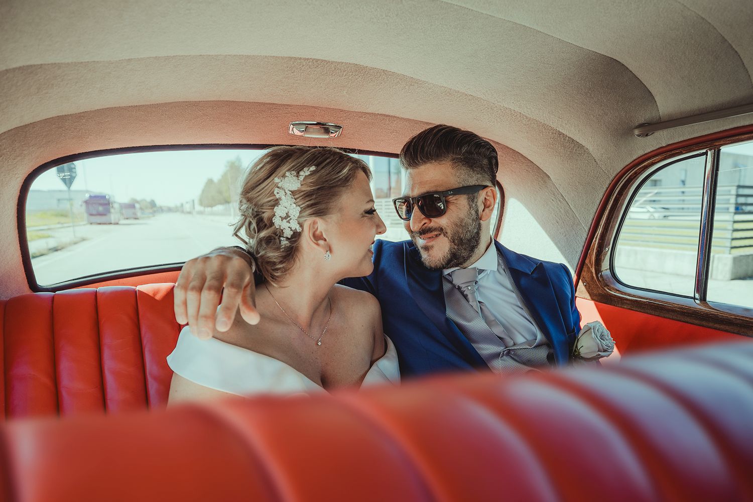 Inside view of a classic car with red leather seats and curved roof design.