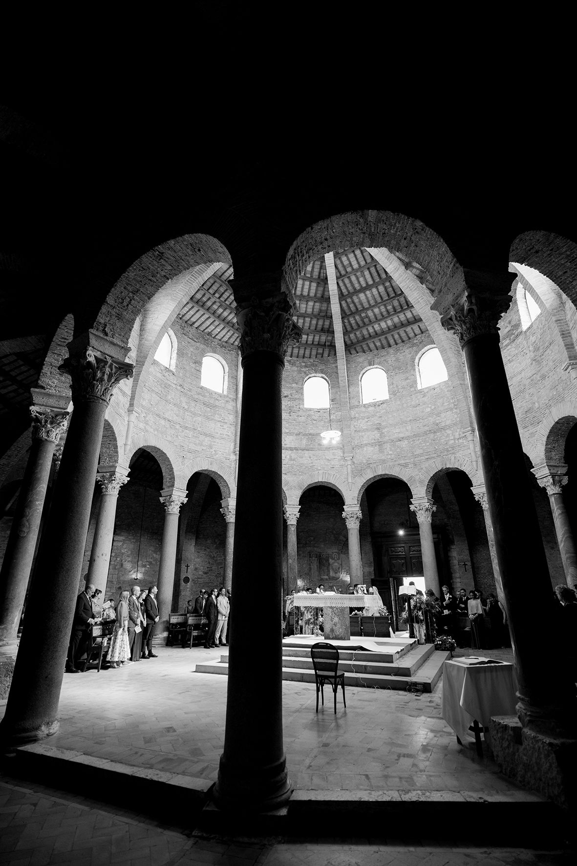 Interior of historic church with dramatic arched columns and domed ceiling in black and white.