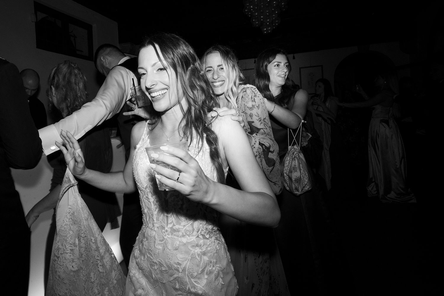 Candid black and white shots of guests dancing and celebrating at a wedding reception.