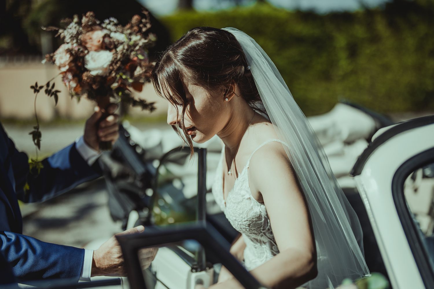 Wedding celebration outdoors with vintage white Volkswagen Beetle in background.