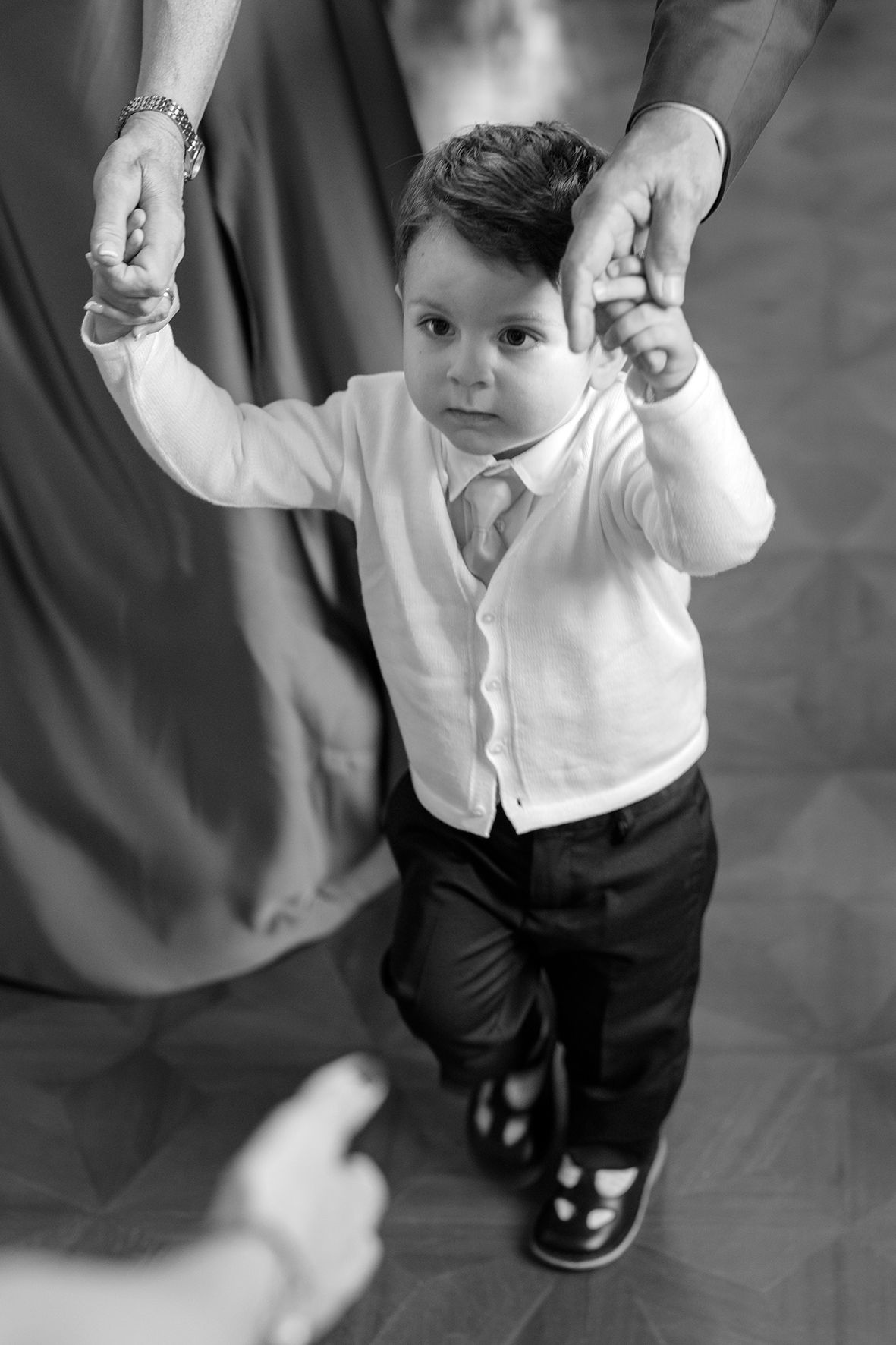 Black and white photo sequence of a small child learning to walk with assistance.