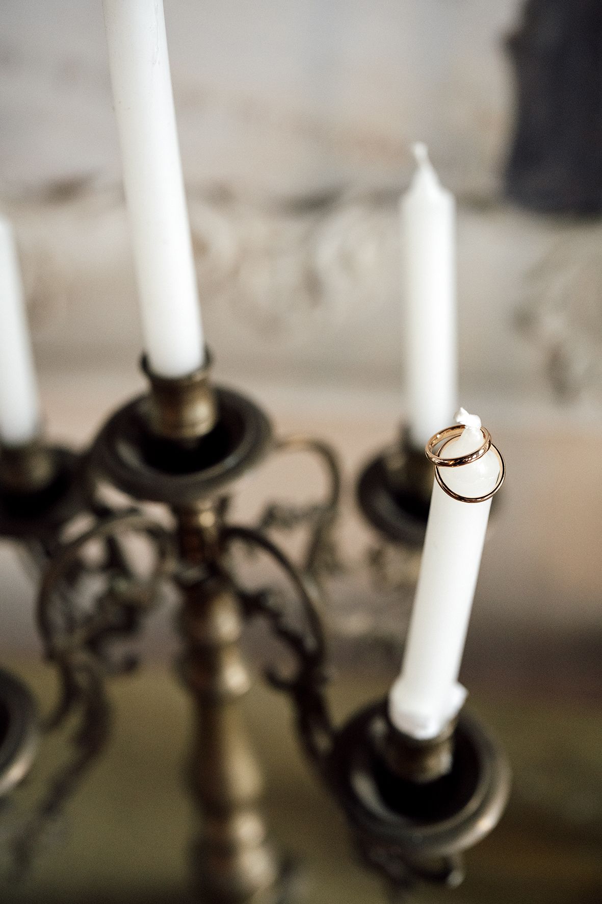 Wedding rings balanced on white candle with brass candlestick holders.