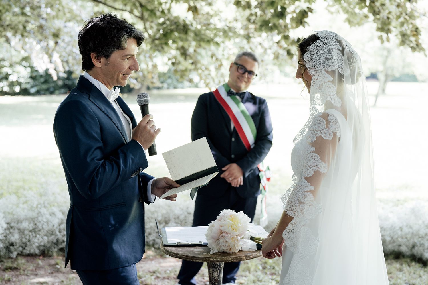 Wedding ceremony sequence showing a couple signing documents under a tree canopy.