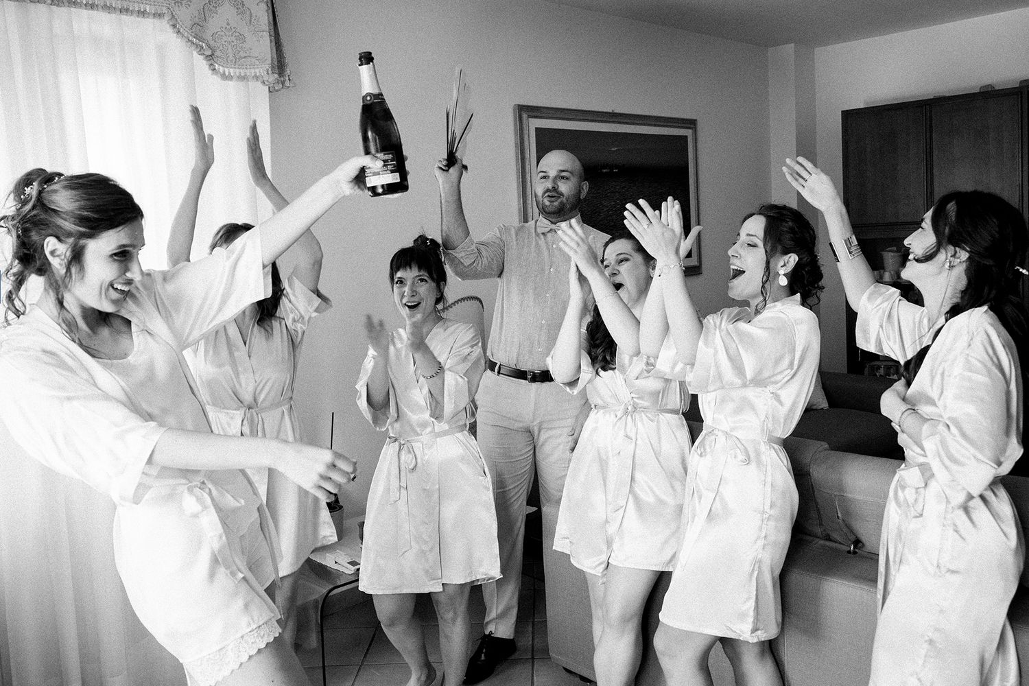 Black and white sequence of bridesmaids celebrating and dancing in matching robes.