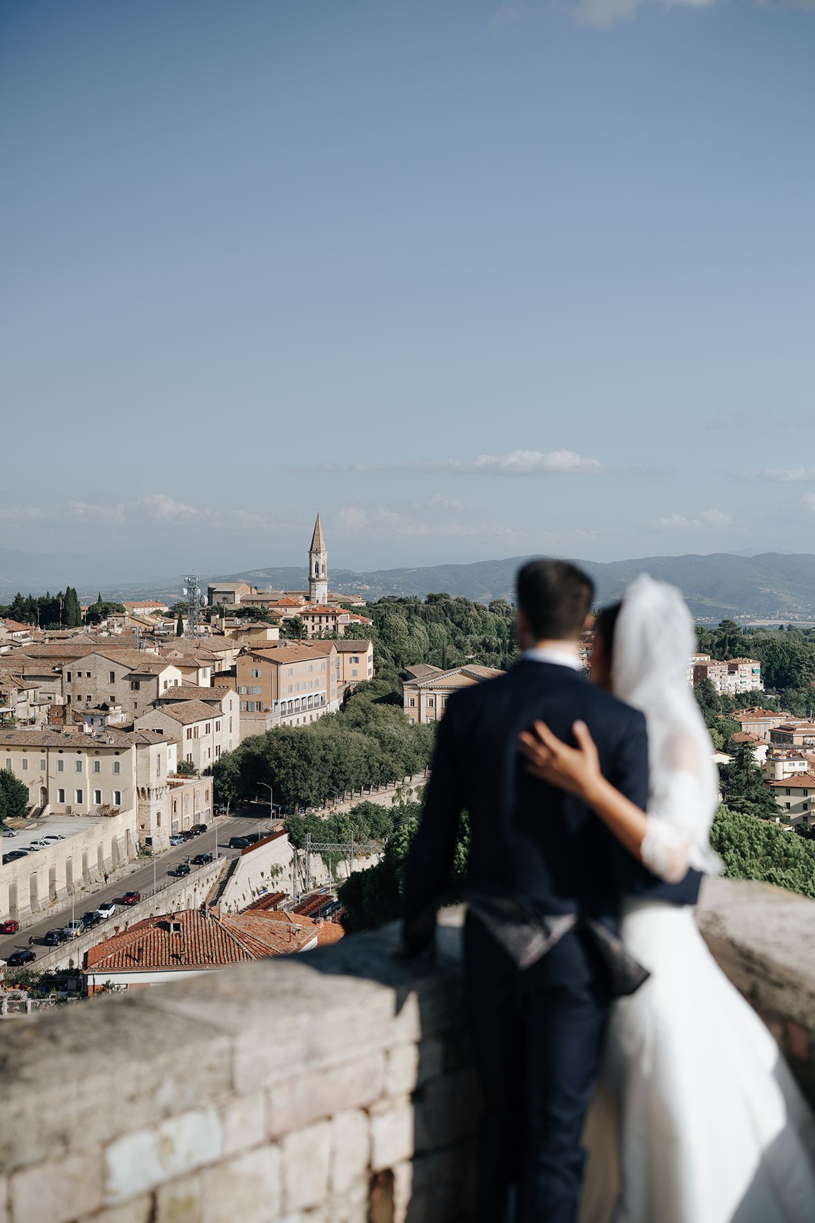 Couple admires panoramic view of Italian hillside town with historic architecture.