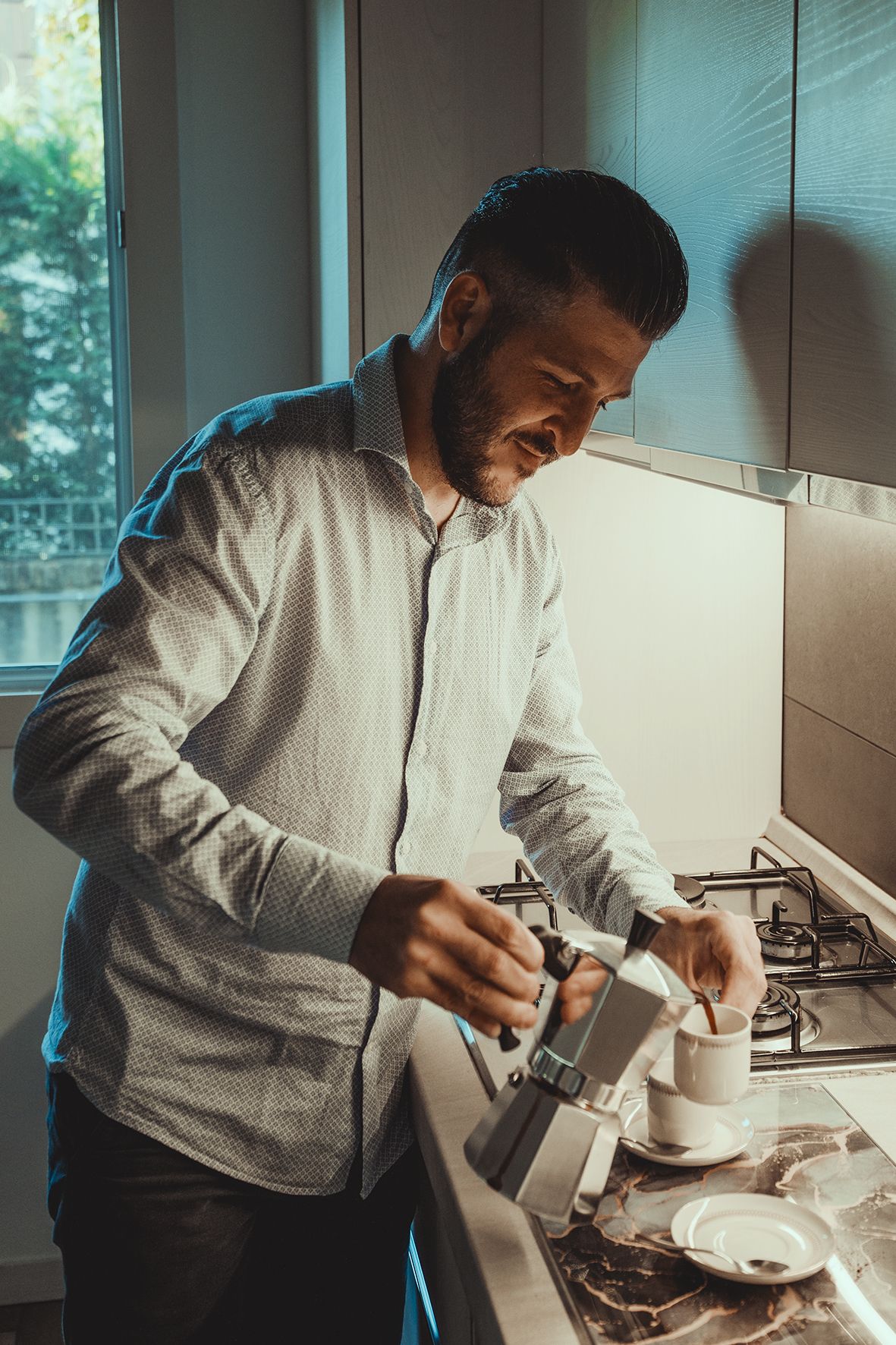 Person in white shirt preparing food in modern kitchen with natural lighting.