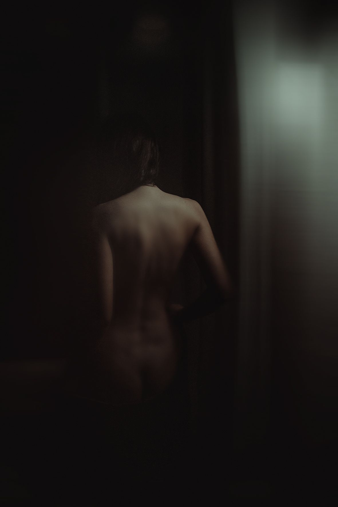 Minimalist study of bare back silhouette in low key lighting.