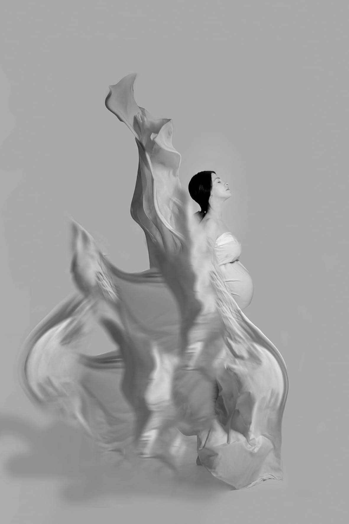 Abstract white shapes creating fluid motion against a light gray background.
