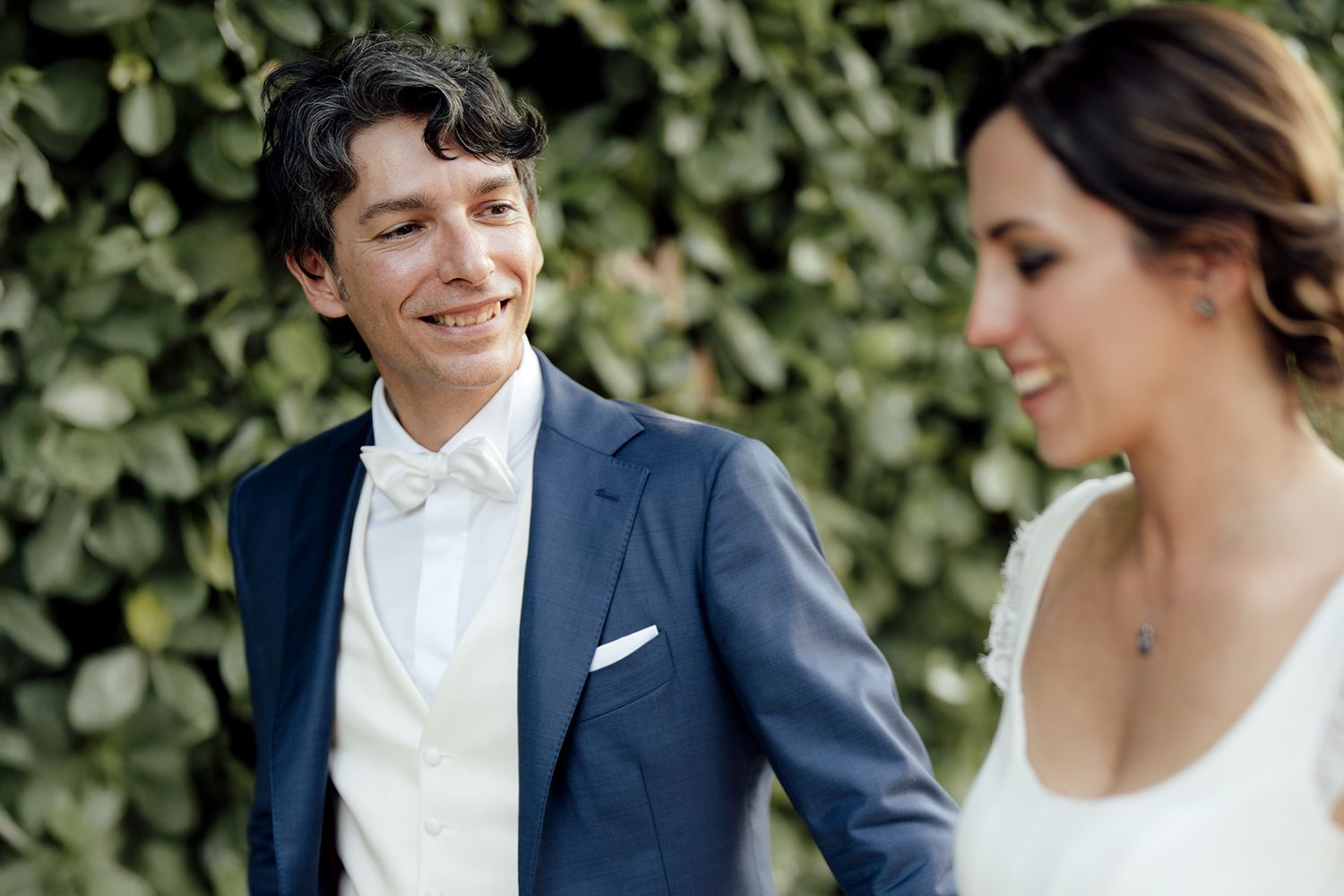 Intimate portrait of newlyweds sharing a tender moment against a leafy backdrop.