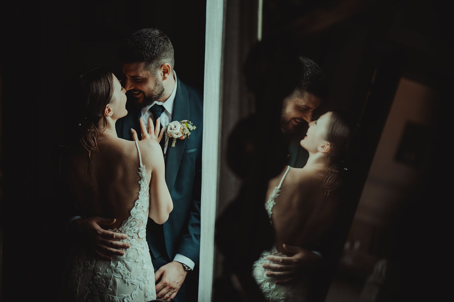 Romantic wedding couple sharing an intimate moment reflected in a window.