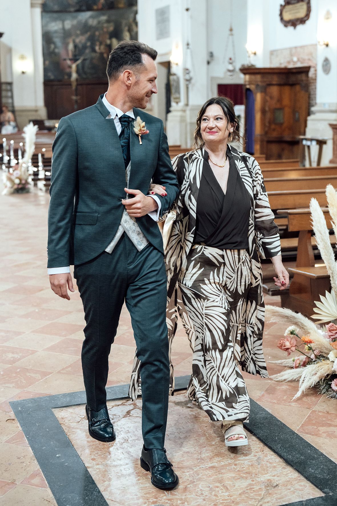 People walking through a church interior with polished floors and elegant decor.