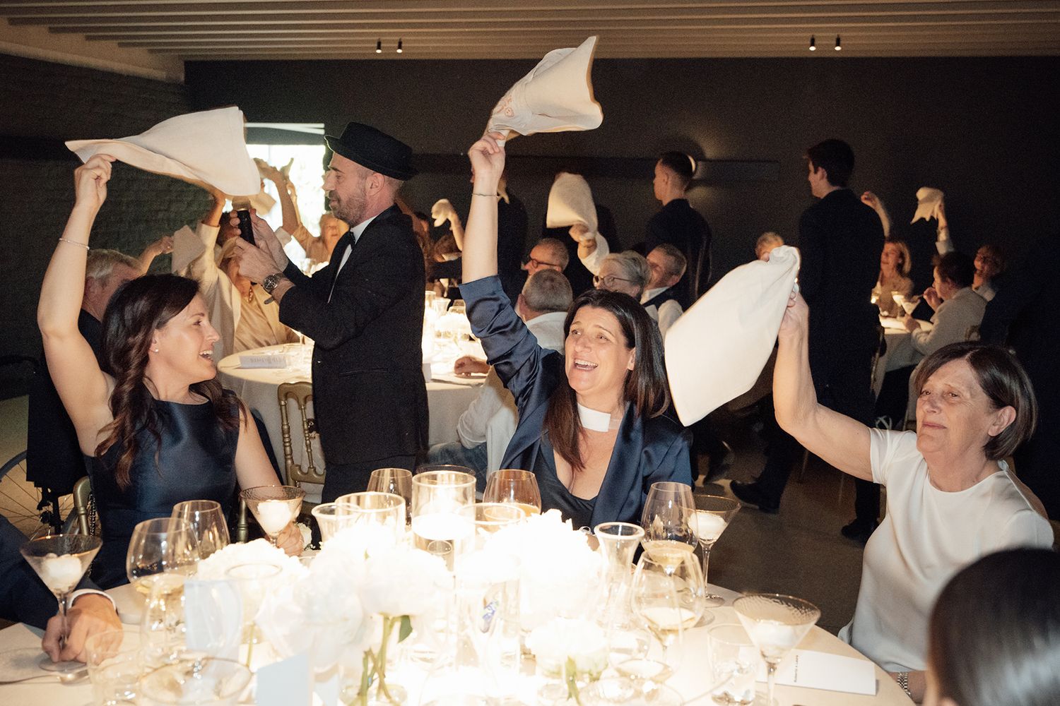 Wedding reception guests celebrate by waving napkins above dining tables.