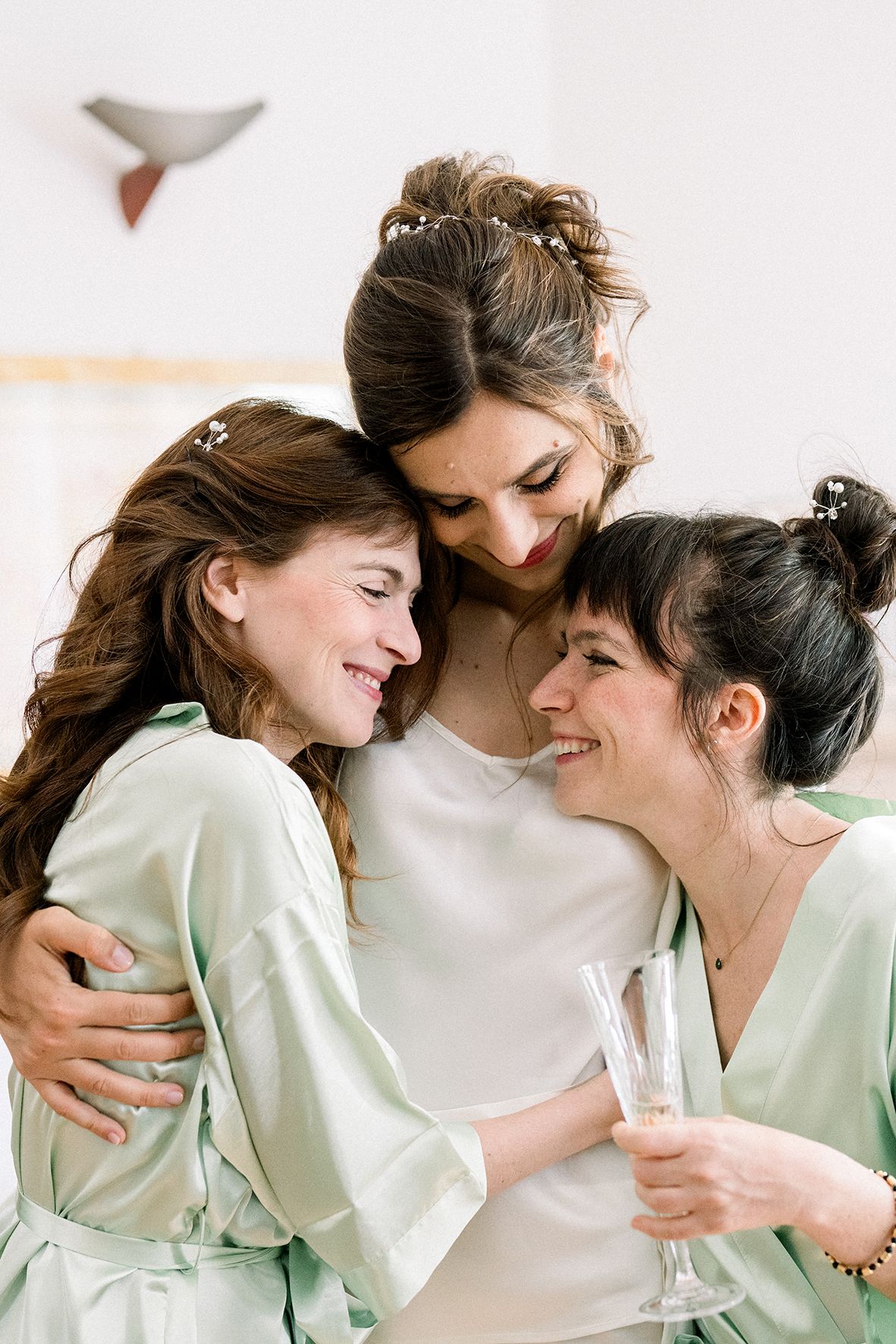 Bridesmaids in mint green and white robes sharing intimate moments.