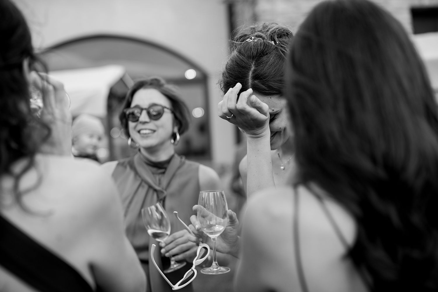 Wedding guests enjoying a celebration with drinks and laughter at an outdoor reception.
