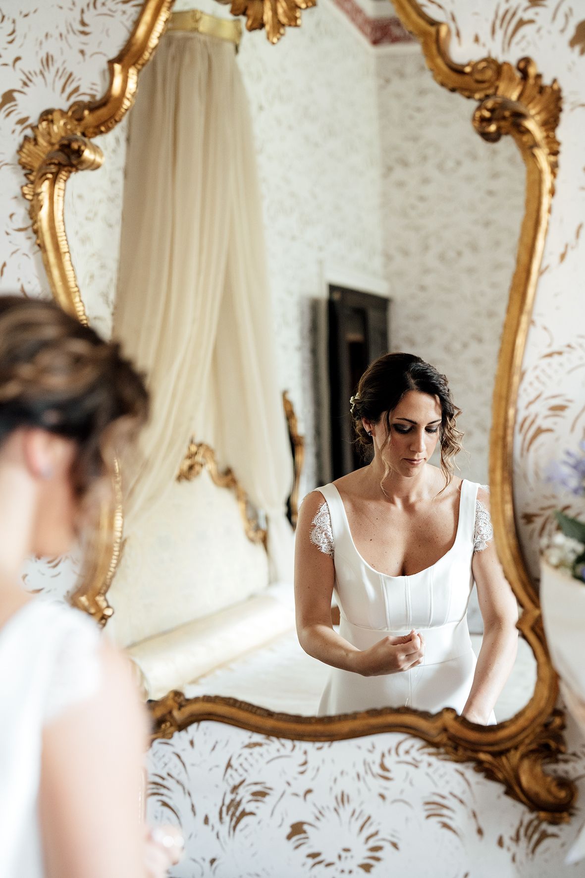 Elegant room with ornate gold-framed mirror and floral wallpaper capturing wedding preparations.