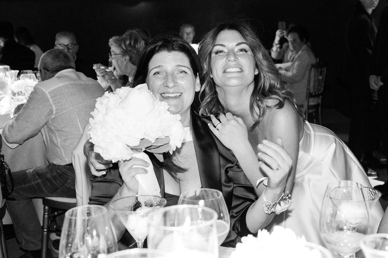 Black and white photos of wedding guests celebrating during reception dinner.