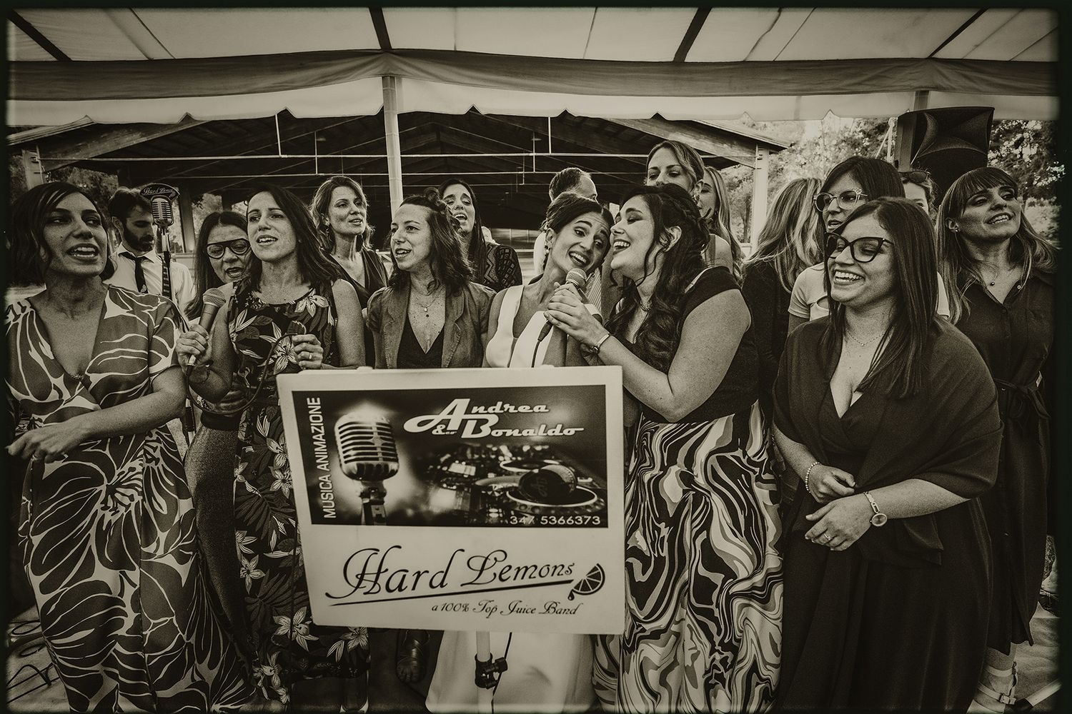 Wedding reception guests dance and celebrate together under a covered outdoor venue with festive lighting.