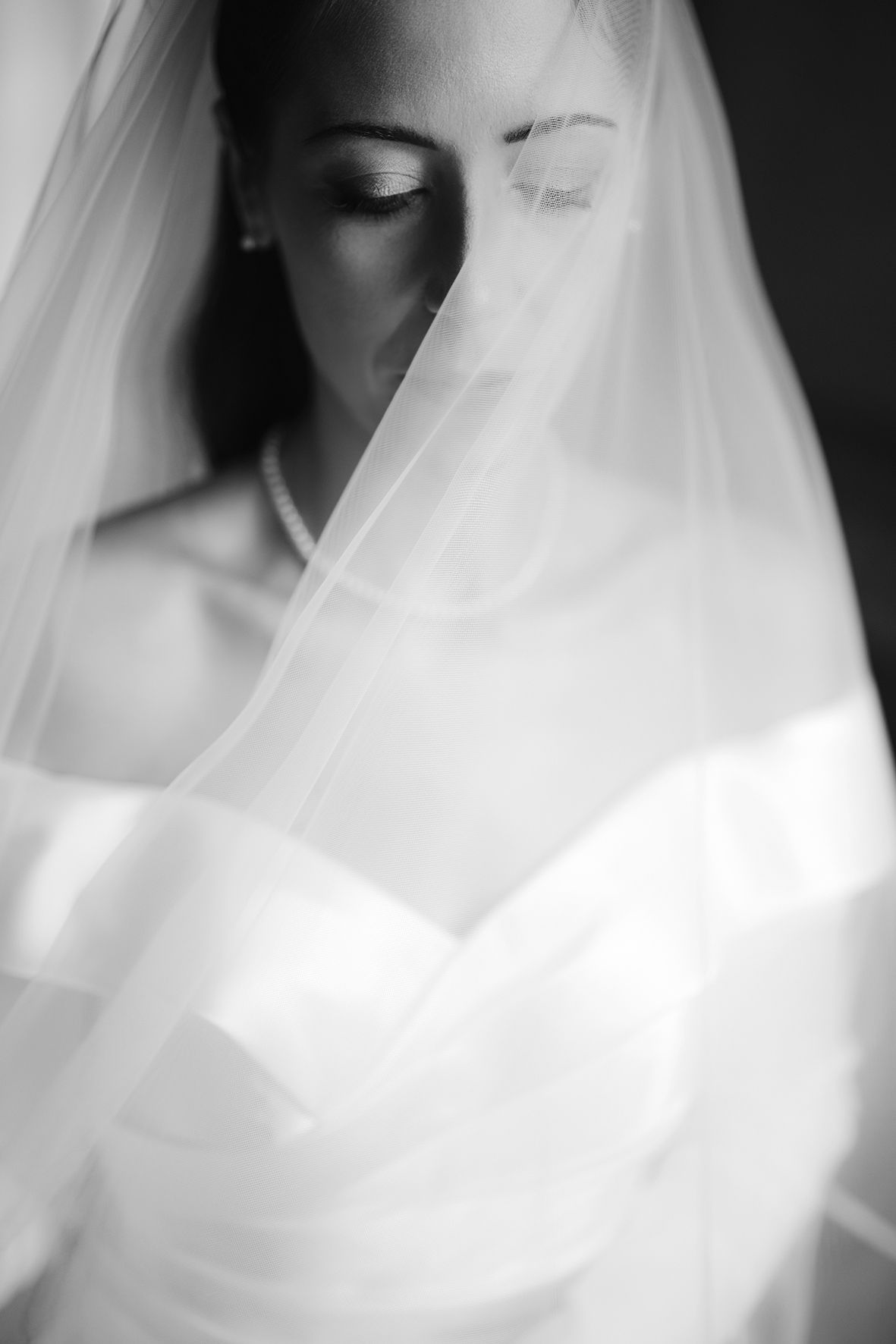 Ethereal black and white portrait of bride with delicate veil creating soft, dreamy effect.